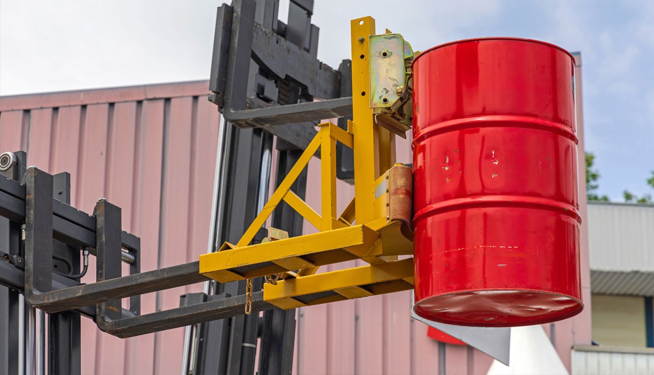 Close up of a forklift drum attachment holding a red drum