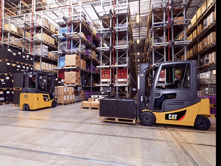 Two CAT forklifts driving in warehouse pallet rack aisles