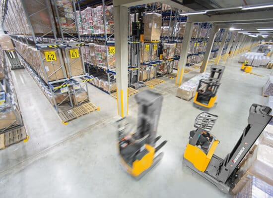 Warehouse with Reach Trucks moving through it
