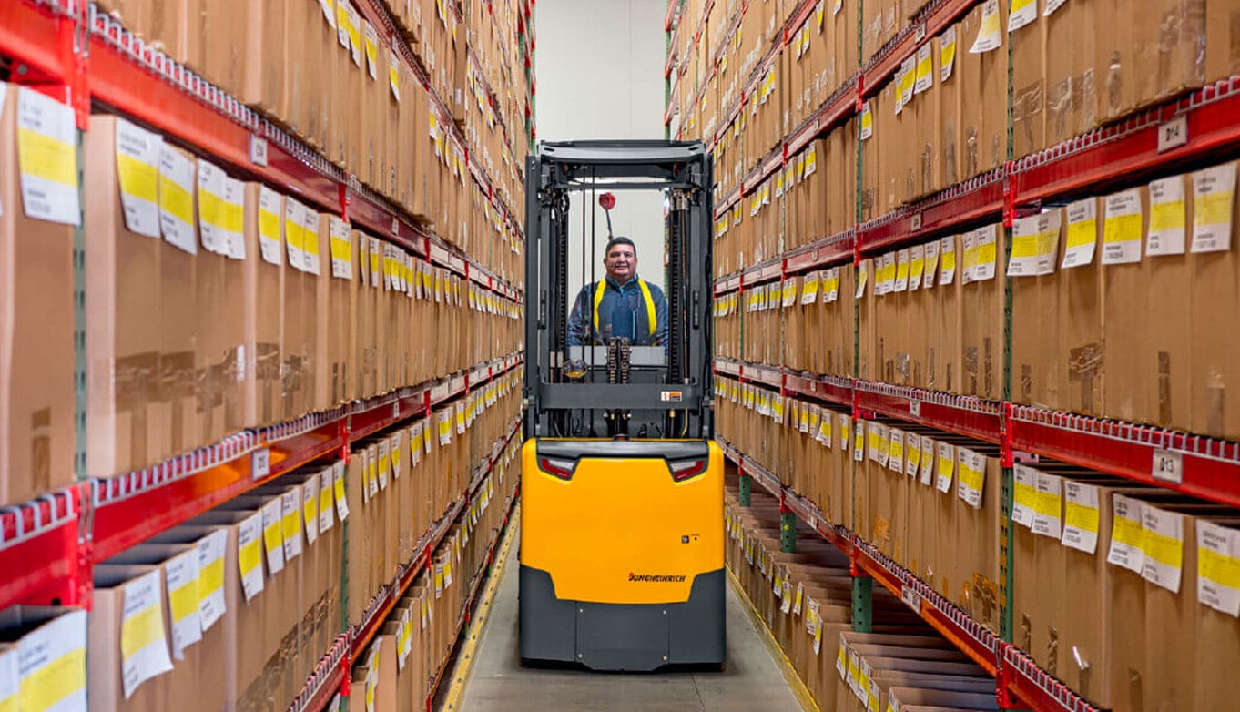 Jungheinrich order picker in between two rows of warehouse shelving