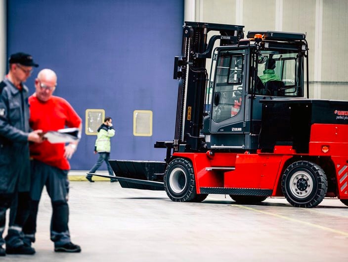 Two men looking at a book next to a Kalmar forklift